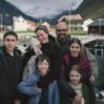 Una familia con cinco hijos posa sonriendo frente a un fiordo noruego en Fjord