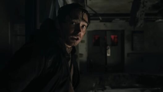 Austin Abrams en la penumbra de un pasillo en Resident Evil