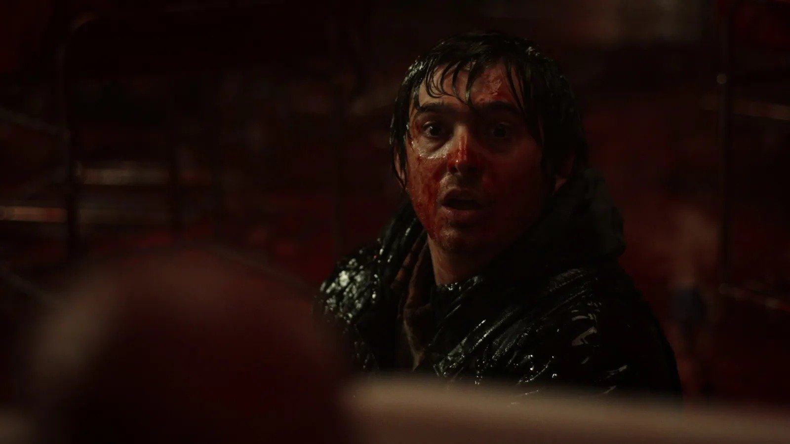 Austin Abrams cubierto de sangre en una escena oscura de Resident Evil