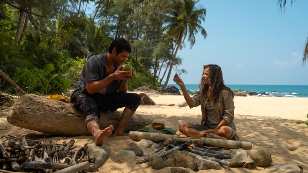 Dylan O'Brien y Rachel McAdams sentados en una playa en Send Help