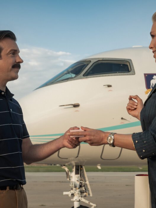 Jason Sudeikis como Ted Lasso estrechando la mano de Rebecca frente a un avión privado