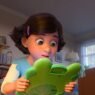 Bonnie sorprendida sosteniendo Lilypad, una tableta verde con forma de rana, en Toy Story 5