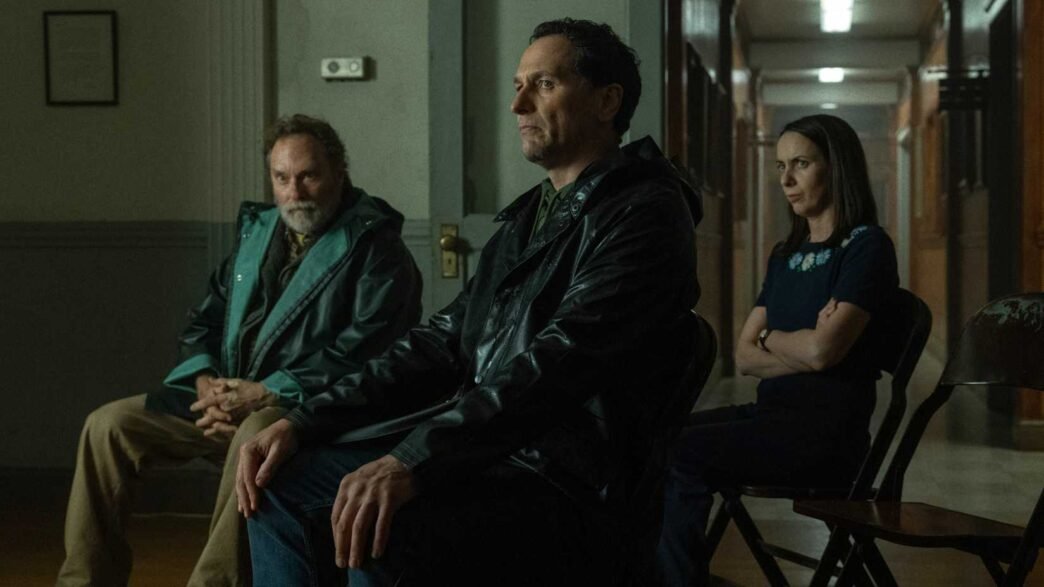 Stephen Root, Matthew Rhys y Kate O'Flynn sentados en un pasillo en Widow's Bay